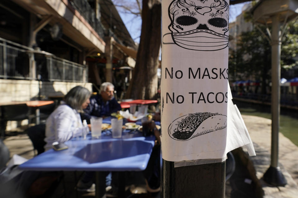 A sign requiring make is seen near diners eating at a restaurant on the River Walk, Wednesday, March 3, 2021, in San Antonio. Gov. Greg Abbott says Texas is lifting a mask mandate and lifting business capacity limits next week. (AP Photo/Eric Gay)