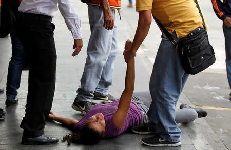 People help a woman overcome by tear gas during a rally against Venezuela's President Nicolas Maduro in Caracas. REUTERS/Christian Veron