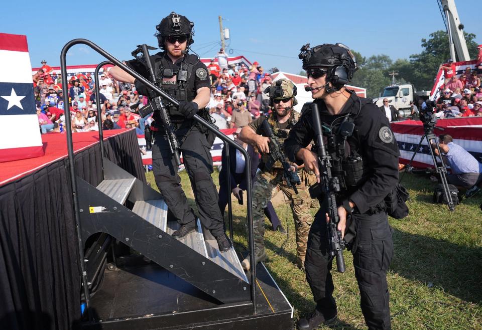 Law enforcement officers with snipers and helmets move around the stage at Trump's campaign rally in Butler, Pennsylvania.