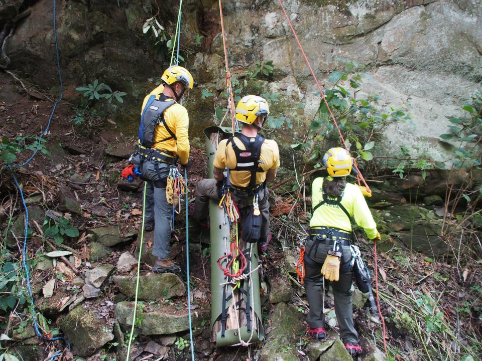 Part of a Smokies search and rescue crew, law-enforcement ranger Wes Mullins straddles the litter — in this case, containing three bundled locust logs — allowing him to monitor the “patient” en route. Fellow law-enforcement ranger Jeff Duckett, on the left, and NPS protection ranger Holly Bates, on the right, serve as attendants and ensure the litter moves freely as it ascends the pitch.