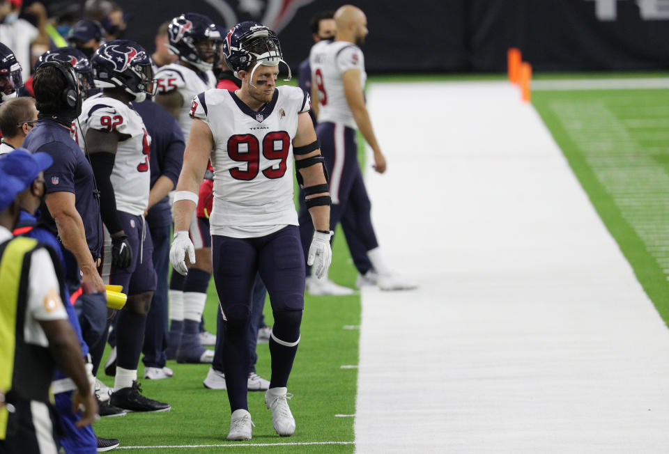 J.J. Watt walks on the sideline with Texans players in the background. 