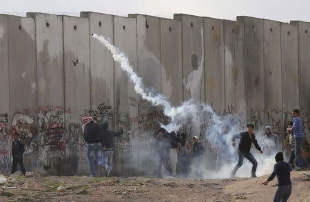 A Palestinian protester returns a gas canter at Israeli troops during clashes following an anti-Israel demonstration in solidarity with al-Aqsa mosque, at Qalandia checkpoint near the West Bank city of Ramallah November 21, 2014. REUTERS/Ammar Awad