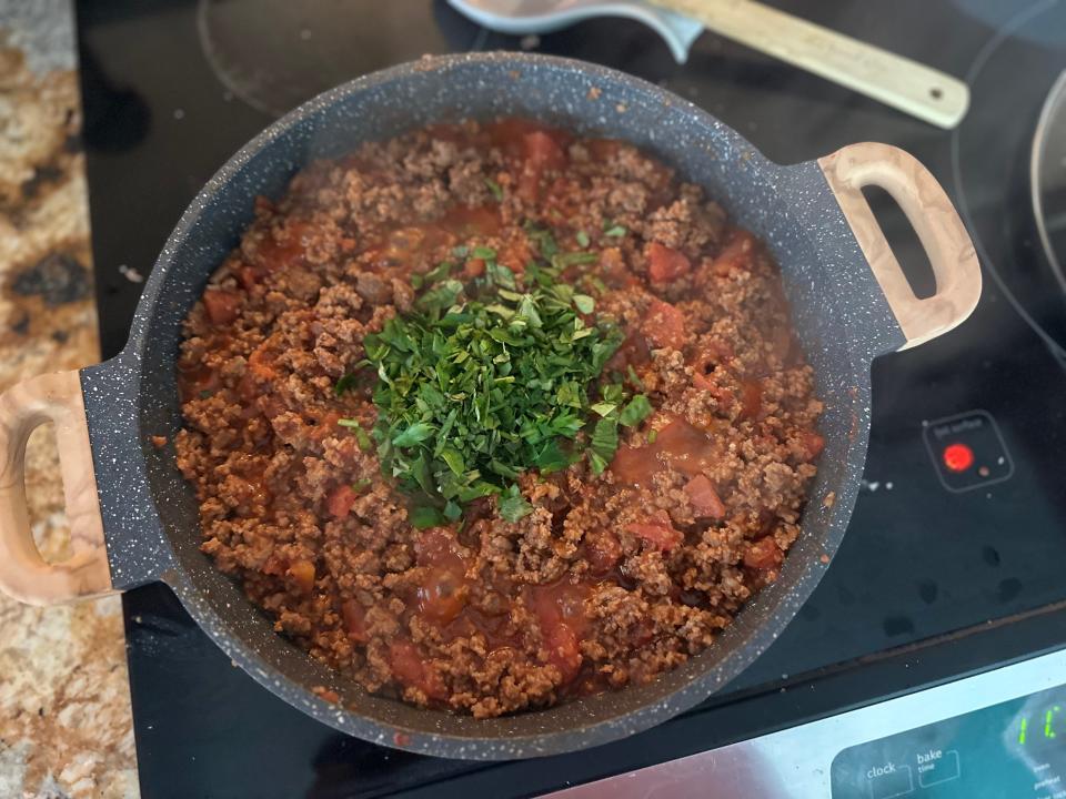 meat sauce with herbs cooking in a pot over the stove