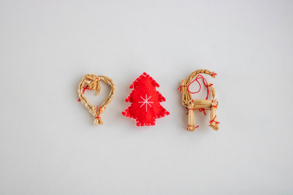 Traditional straw toys and a red Christmas tree on a white background.