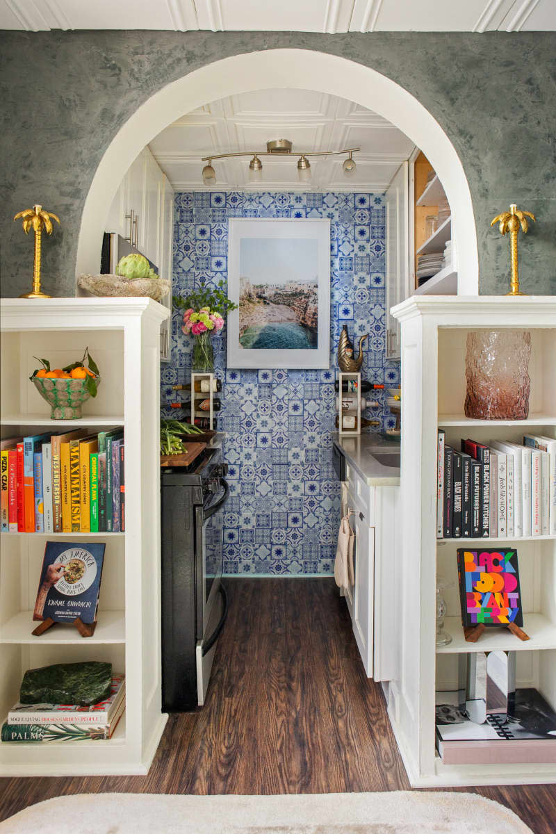 view through arched doorway into blue and white kitchen with wallpaper accent wall