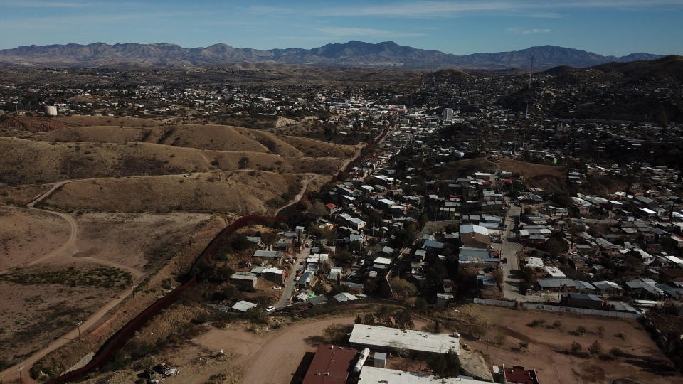 The U.S. border fence separates Nogales, Mexico, right, from sister city Nogales, Arizona, left, Friday, Jan. 3, 2020. Dozens of asylum seekers pushed back into Mexico by the United States tried Friday to get their bearings still unsure of how they would travel some 350 miles to their court dates in El Paso, subsist for months in this unfamiliar border city or return to their distant homelands. (AP Photo/Luis Enrique Castillo)