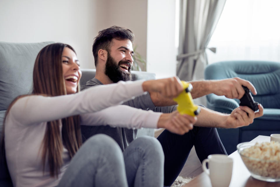 A man and a woman play a video game in a living room