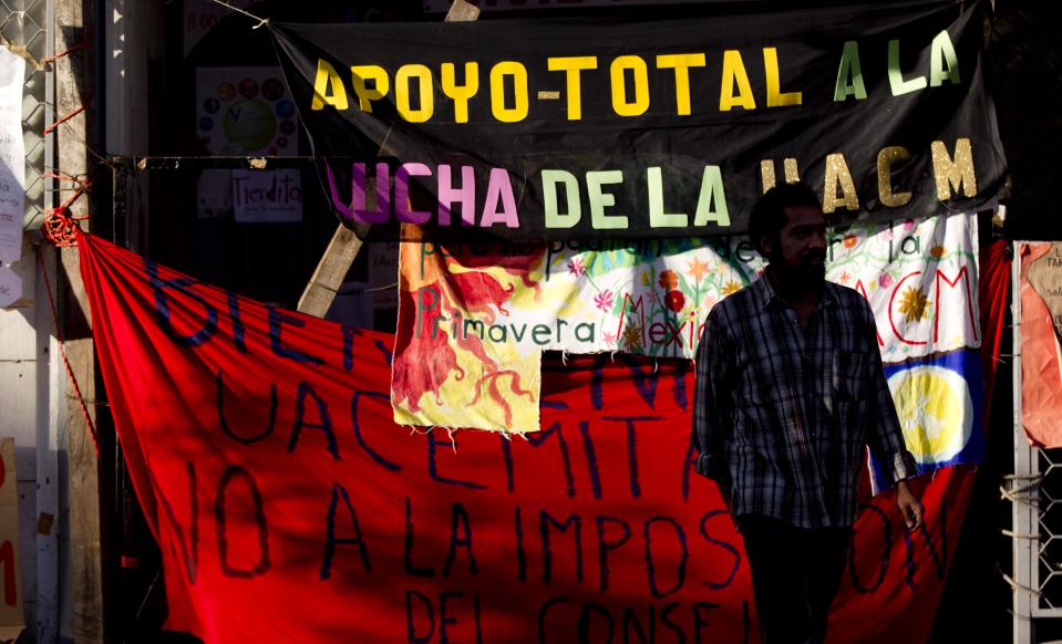 In this photo taken Thursday, Oct. 11, 2012, a student participating in a student strike walks past protest banners at the Autonomous University of Mexico City, in Mexico City. Students fed up with lost class time are seizing back their campuses, showing little nostalgia for Mexico's radical traditions. This month, about 100 students at Mexico City's Autonomous University rushed the gates of their seized campus and briefly forced out striking students, who later returned with a pickup truck to bash in the gates and retake the school. The two sides are now in talks to end the standoff. (AP Photo/Eduardo Verdugo)