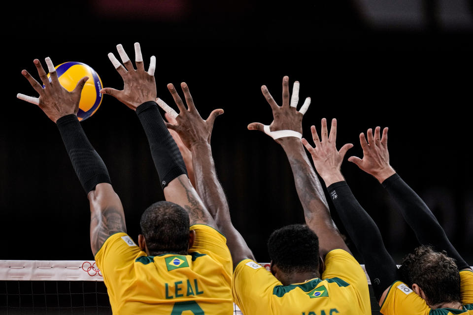 Brazil's team players block a ball during a men's volleyball preliminary round pool B match between Brazil and United States at the 2020 Summer Olympics, Friday, July 30, 2021, in Tokyo, Japan. (AP Photo/Manu Fernandez)
