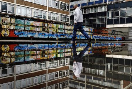 A man passes graffiti near the Old Street roundabout dubbed "Silicon Roundabout" in London May 28, 2013 in this May 28, 2013 file photo. REUTERS/Luke Macgregor/Files