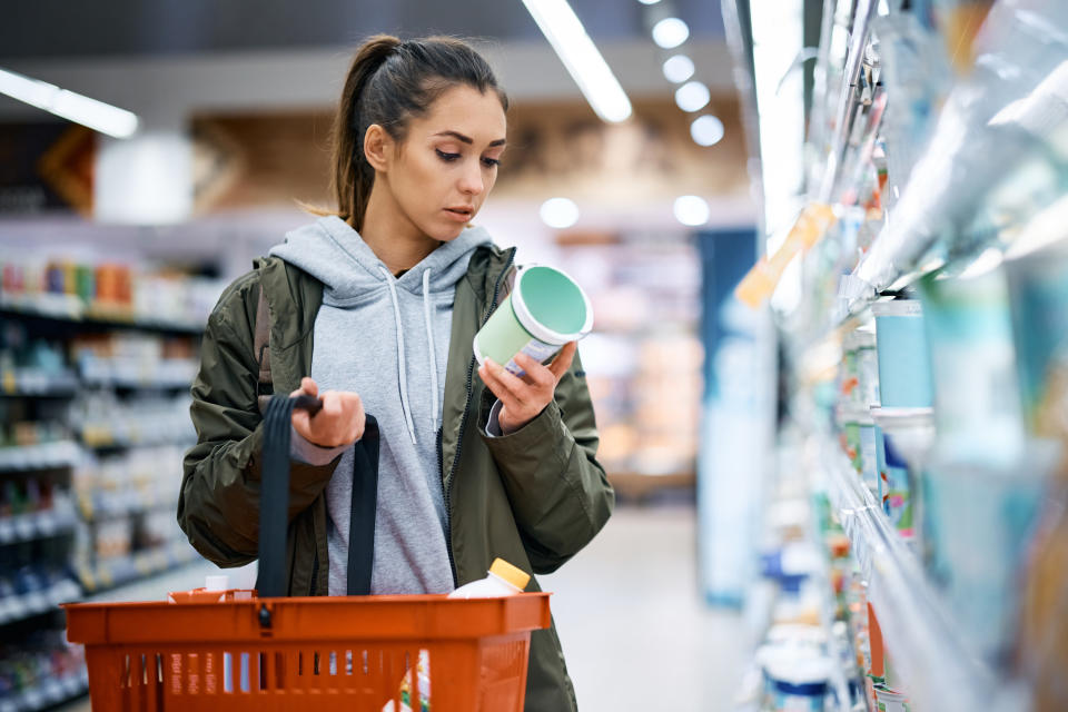 person buying diary product and reading food label in grocery store