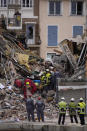 Rescue workers inspect the rubbles at a three-story apartment building after it collapsed in a suspected gas explosion on southern France's Mediterranean coast, Tuesday, Dec. 7, 2021 in Sanary-sur-Mer. French rescue workers dug out the body of a man but also pulled a toddler and the child's mother alive from the rubble of the building that collapsed in a suspected gas explosion. Two other people are missing. (AP Photo/Daniel Cole)