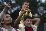 Migrants look up at a press camera drone as they walk along the Huehuetan highway in Chiapas state, Mexico, early Tuesday, June 7, 2022. The group left Tapachula on Monday, tired of waiting to normalize their status in a region with little work and still far from their ultimate goal of reaching the United States. (AP Photo/Marco Ugarte)