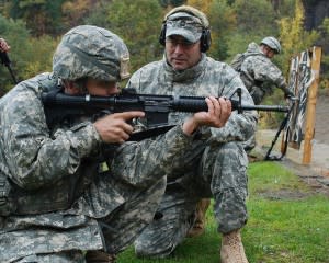 Soldier aiming rifle, with instructor next to him