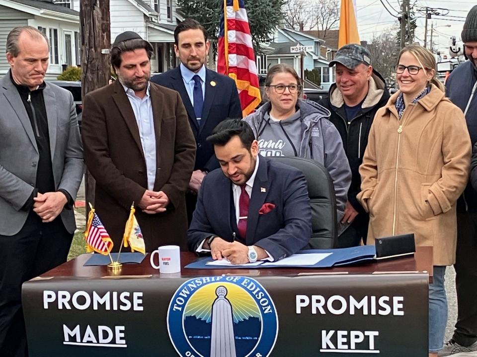 Edison Mayor Sam Joshi, joined by residents and some township officials, signs paperwork acquiring an 11-acre site in the southern part of the township where a huge warehouse had been planned, a project neighborhood residents had fought.