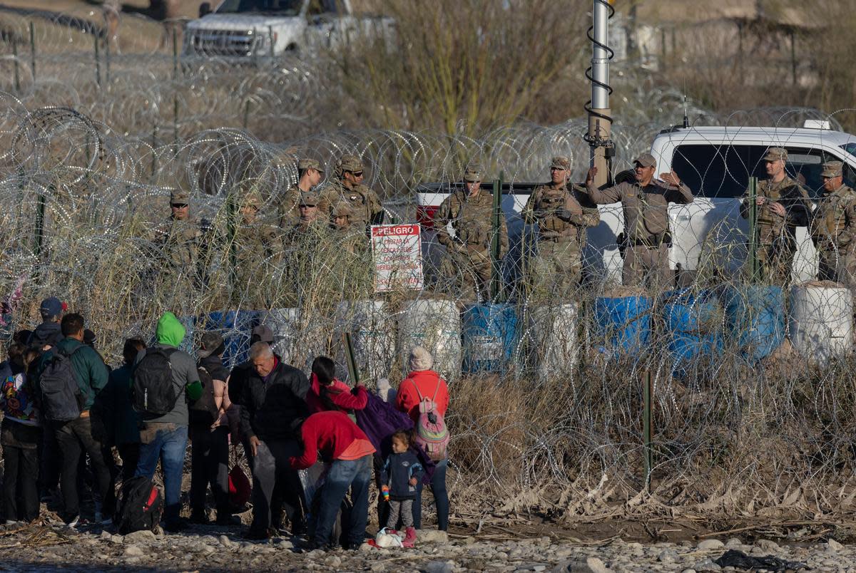 Migrants speak with a State Trooper at the bank of the Rio Grande at Shelby Park in Eagle Pass, on Jan. 19, 2024.