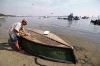 A fisherman cleans his boat on Fundao beach in the Guanabara Bay in Rio de Janeiro March 13, 2014. According to the local media, the city of Rio de Janeiro continues to face criticism locally and abroad that the bodies of water it plans to use for competition in the 2016 Olympic Games are too polluted to host events. Untreated sewage and trash frequently find their way into the Atlantic waters of Copacabana Beach and Guanabara Bay - both future sites to events such as marathon swimming, sailing and triathlon events. REUTERS/Sergio Moraes (BRAZIL - Tags: ENVIRONMENT SPORT OLYMPICS)