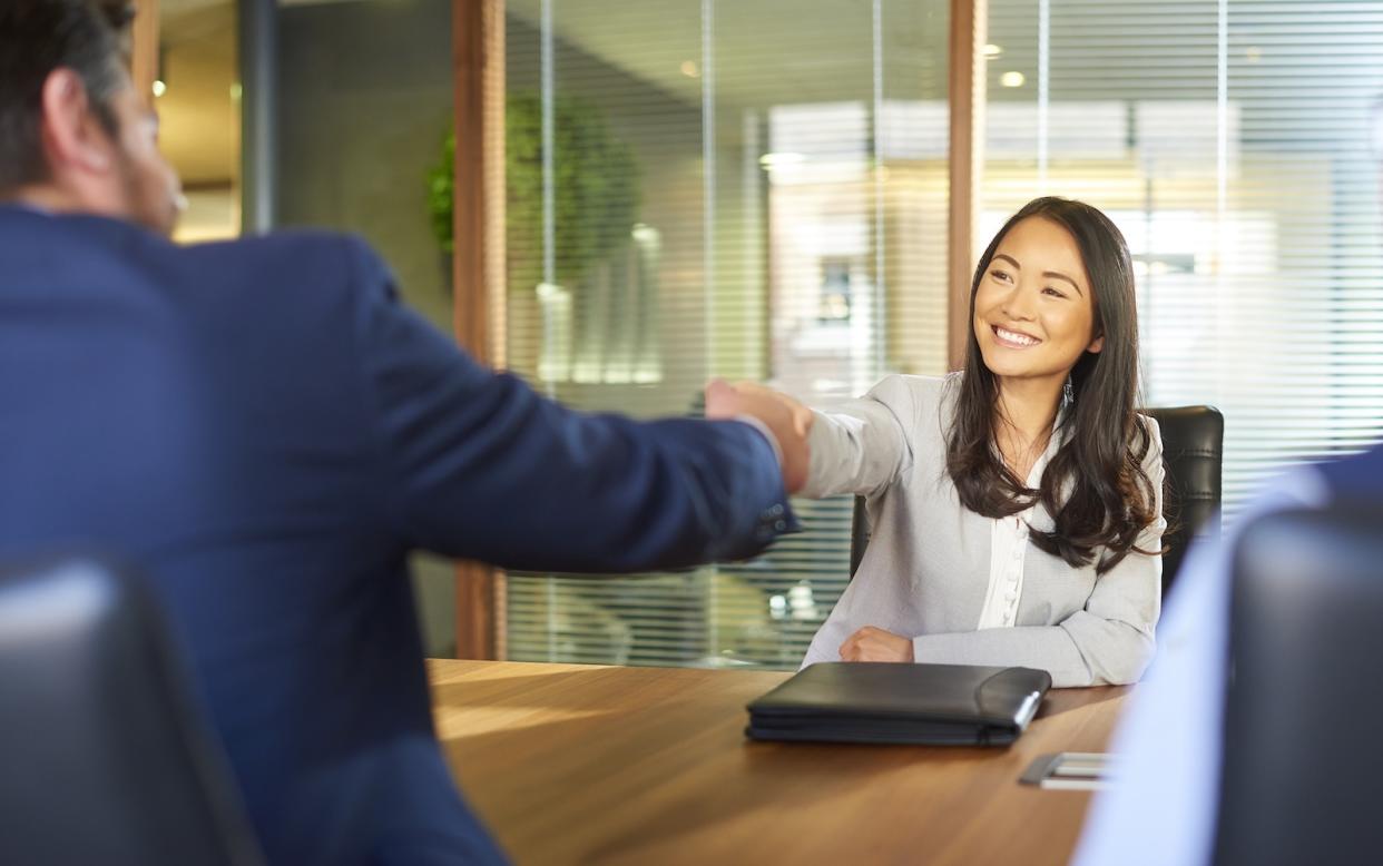 An asian lady shaking hands with her boss, illustrating a story on low salary increments and job hopping.