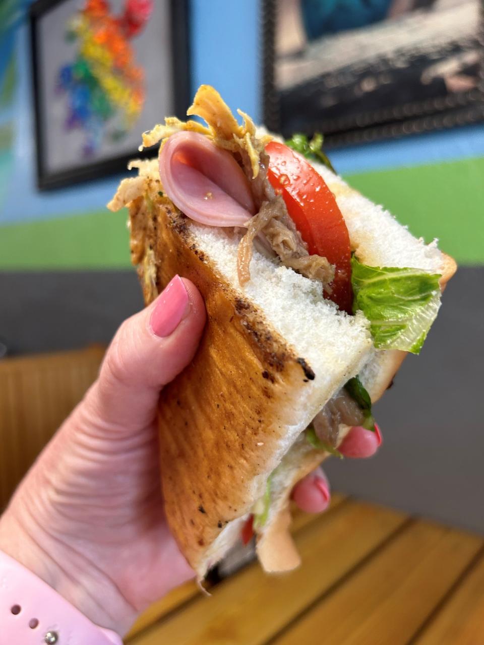 The Tripleta Sandwich at the Tiny Turtle in Cocoa Beach features roasted island pork, braised island chicken, savory sweet ham, pepper jack cheese, romaine, tomato, potato sticks and Creme Caribe on pressed Puerto Rican sobao bread.
