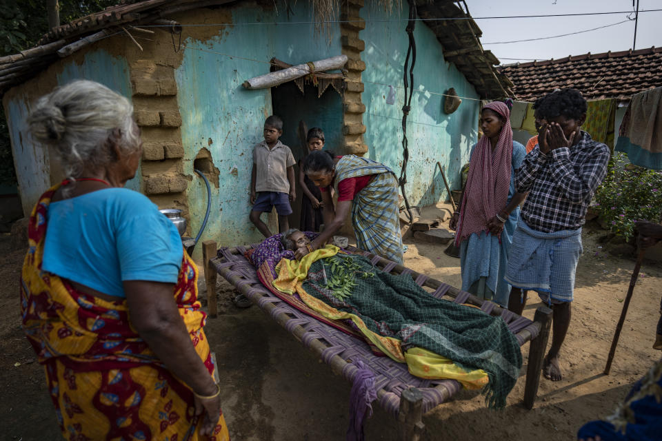 Family members stand next to the body of an elderly tribes woman after she passed away in Donkasai village in the eastern Indian state of Jharkhand, Oct. 20, 2022. India's 110 million indigenous tribespeople scattered across various states and fragmented into hundreds of clans, with different legends, different languages and different words for their gods adhere to Sarna Dharma - a faith not officially recognized by the government. It is a belief system that shares common threads with the world's many ancient nature-worshipping religions. (AP Photo/Altaf Qadri)