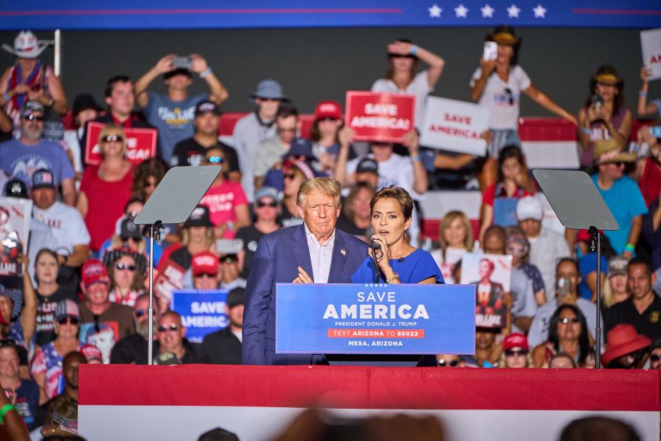 Gubernatorial candidate Kari Lake, flanked by former President Donald Trump, delivers remarks during Trump's rally at Legacy Sports Park in Mesa on Sunday, Oct. 9, 2022.