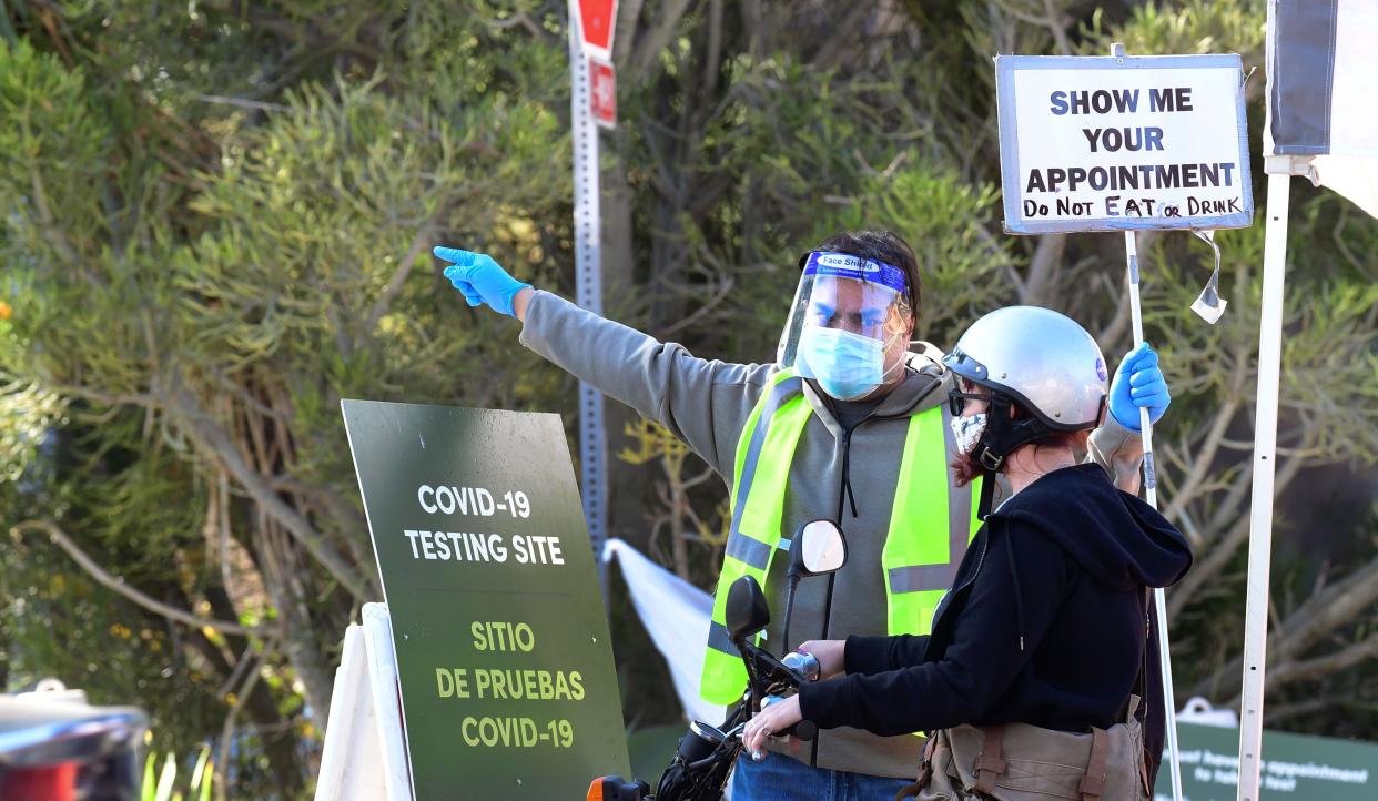 A volunteer gives directions as people arrive and depart from the COVID-19 testing venue at Dodger Stadium in Los Angeles, California on Nov. 12, 2020.