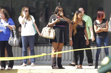 Parents and onlookers stand behind police tape after a vehicle crashed into a child care center in Winter Park, Florida April 9, 2014. REUTERS/Stephen M. Dowell/Orlando Sentinel