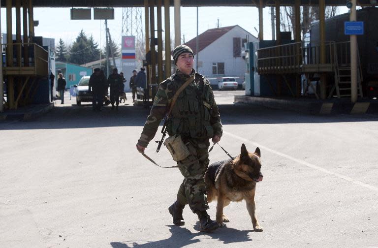 Ukrainian border guard patrols with his dog at the Uspenka check point on the border between Ukraine and Russia, some 120 km from the eastern city of Donetsk on March 21, 2014