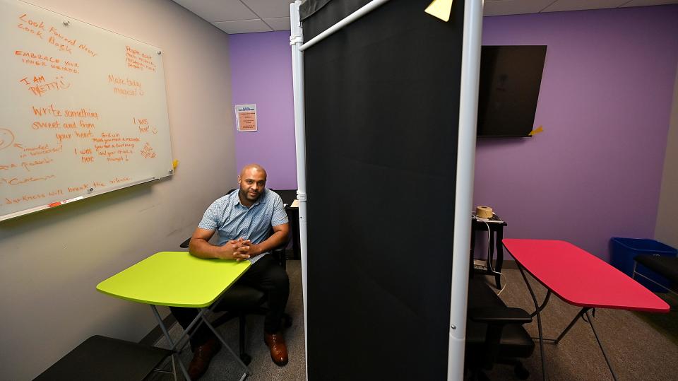 Worcester Department of Public Health Clinical Consultant Henock Assefa in his work area at AIDS Project Worcester. The white board bears messages from clients.