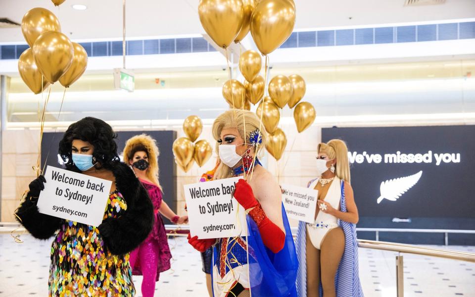  Members of the "welcome back drag committee" greet passengers arriving from New Zealand at Sydney International Airport, as the trans-Tasman travel bubble between New Zealand and Australia begins - Jenny Evans/Getty Images