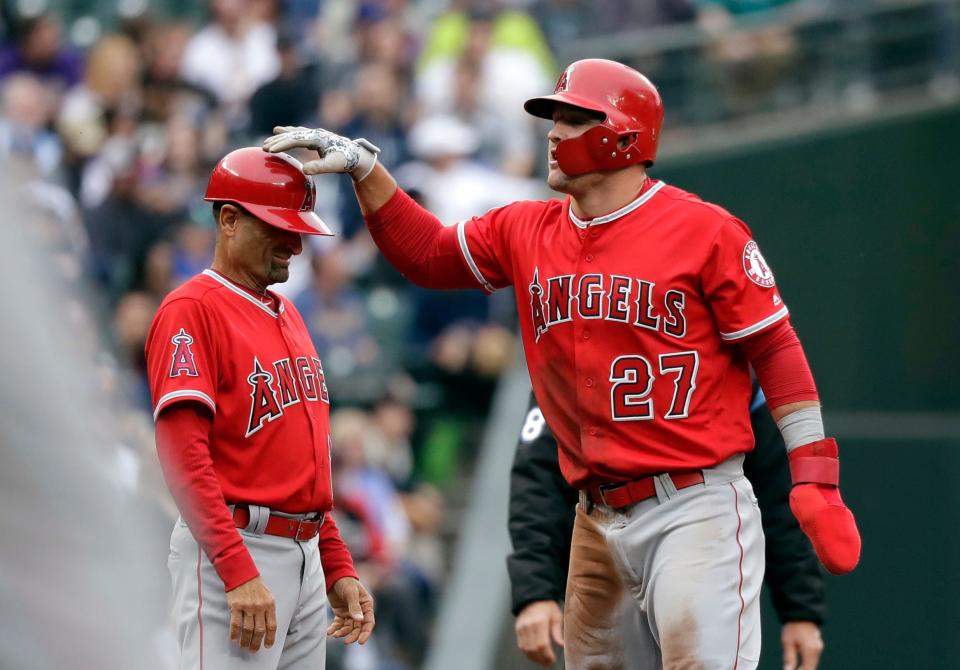 Los Angeles Angels' Mike Trout, right, gives a pat to third base coach Dino Ebel during a game against the Seattle Mariners on May 5, 2018, in Seattle.