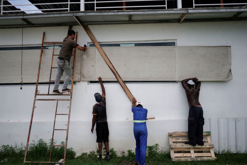 Workers protect the windows of a bar in anticipation of the Tropical Storm Laura arrival, in Havana