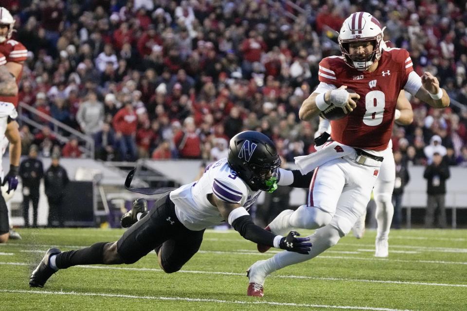 Wisconsin's Tanner Mordecai (8) tries to run past Northwestern's Jaheem Joseph (3) during the second half of an NCAA college football game Saturday, Nov. 11, 2023, in Madison, Wis. (AP Photo/Morry Gash)