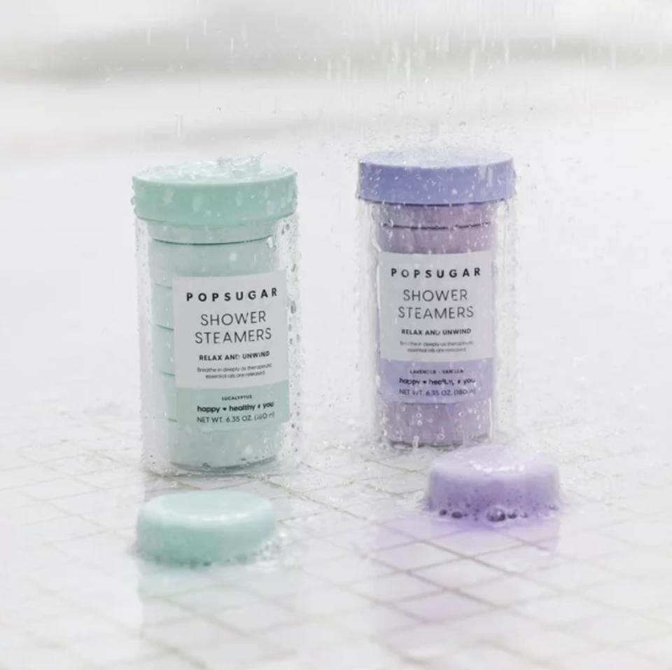 Two shower steamer bottles with tablets on a wet surface, labeled "POPSUGAR" for relaxation
