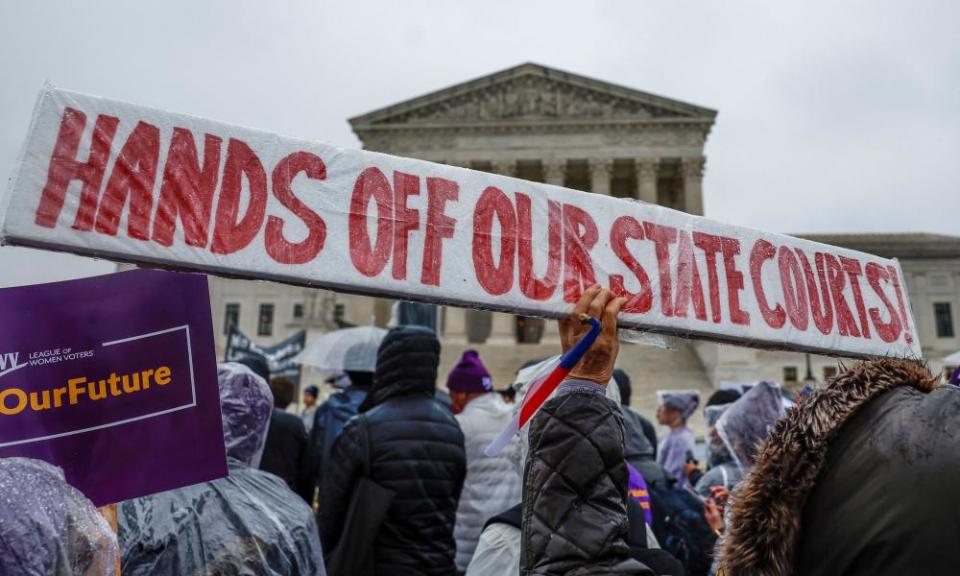 Demonstrators gather outside of the United States Supreme Court as the justices hear oral arguments in Moore v Harper.