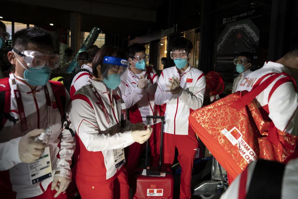 <p>Members of China's tennis table team disinfect their gloves as they arrive for the Tokyo 2020 Olympic Games at Narita International Airport in Narita, Chiba prefecture on July 17, 2021. (Photo by Charly TRIBALLEAU / AFP)</p> 