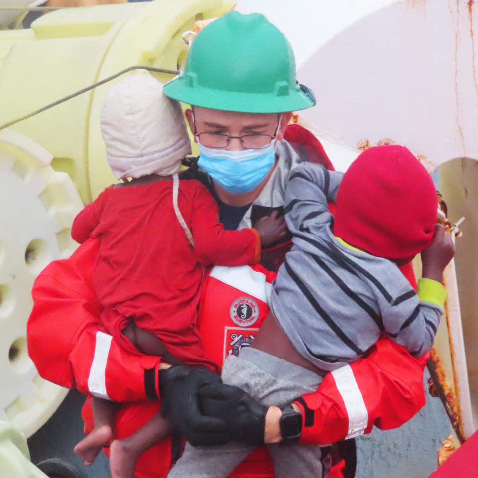 A U.S. Coast Guard official carries two children on Monday.  (@USCGSoutheast / Twitter)