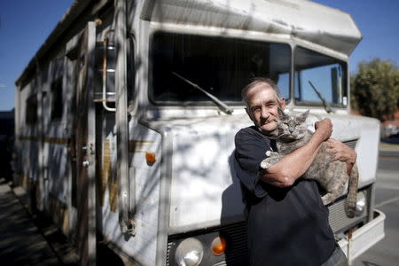 Dan, 68, holds one of his three cats as he poses for a portrait by the motorhome in which he lives on the streets of Los Angeles, California, United States, November 12, 2015. REUTERS/Lucy Nicholson