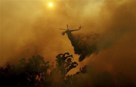 A helicopter drops water on a wildfire in Fallbrook, California May 14, 2014. REUTERS/Sandy Huffaker