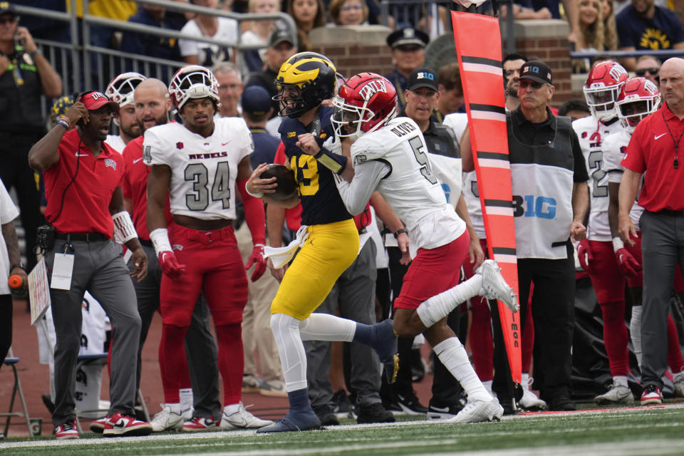 Michigan quarterback Jack Tuttle (13) is pushed out of bounds by UNLV defensive back Cameron Oliver (5) in the second half of an NCAA college football game in Ann Arbor, Mich., Saturday, Sept. 9, 2023. (AP Photo/Paul Sancya)