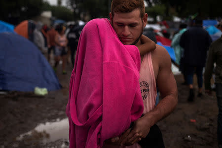 A migrant man, part of a caravan of thousands from Central America trying to reach the United States, holds his child during rainfall at a shelter in Tijuana, Mexico November 29, 2018. REUTERS/Adrees Latif