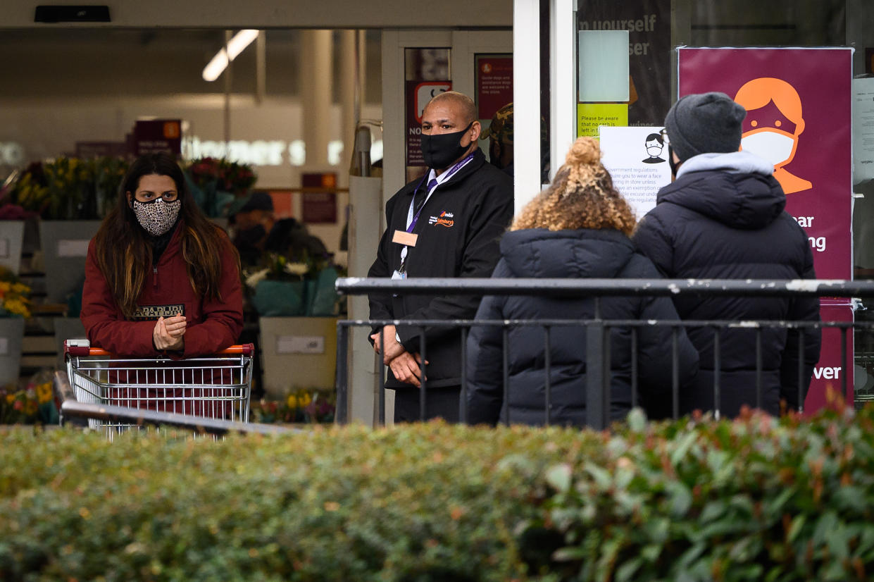 LONDON, UNITED KINGDOM - JANUARY 12: A security guard (C) stands at the entrance to a branch of the Sainsbury's supermarket chain following the company's decision to enforce the mandatory wearing of face masks in their stores, on January 12, 2021 in London, United Kingdom. In response to government ministers voicing concerns about the public's behaviour in supermarkets, Sainsbury's and Morrisons have both announced they will be enforcing rules on mask-wearing in their stores. The daily admissions to hospitals of coronavirus cases  has topped 4000 and the current number of patients in hospital with the virus is 32,294. (Photo by Leon Neal/Getty Images)