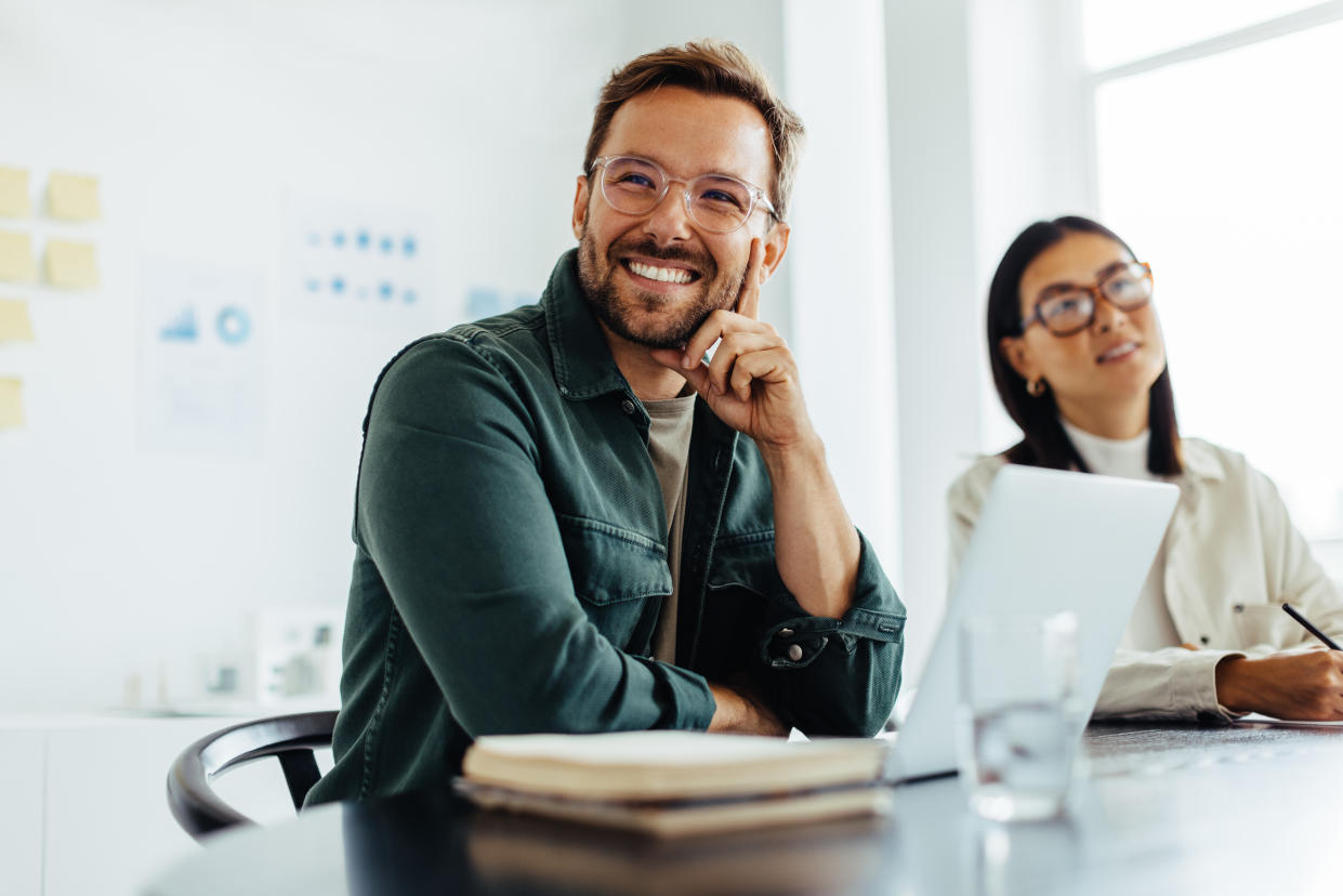 Business man listening to a employees discussion during a meeting in an office. Happy business man sitting in a boardroom with his colleagues.