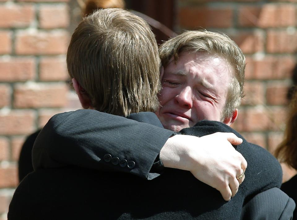 Friends hug after the funeral of Josh Hunter in Calgary