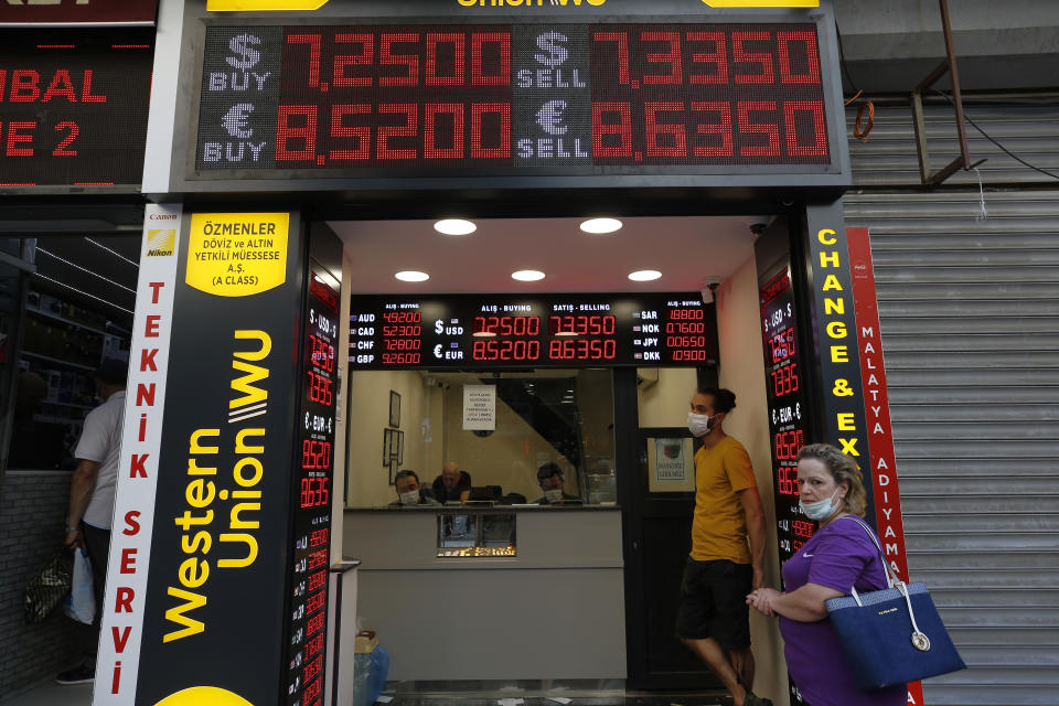 People stand outside an exchange office in Istanbul, Friday, Aug. 7, 2020. Turkey's currency tumbled further Friday, hitting another record low. The Turkish lira dropped to 7.3677 against the dollar before making a recovery. The lira is down about 19% versus the U.S. currency since the beginning of the year. (AP Photo/Emrah Gurel)