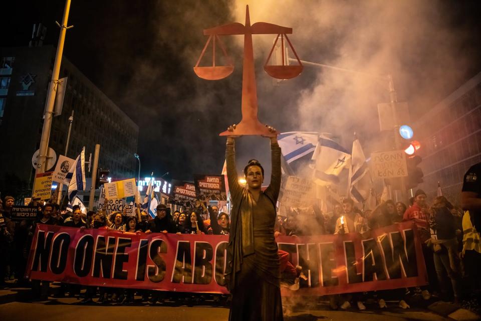 A protester raises a ‘scales of justice’ symbol during a demonstration on Feb. 11, 2023, in Tel Aviv, where 130,000 people marched against Israel’s right-wing government and its controversial legal reform. <a href="https://www.gettyimages.com/detail/news-photo/protester-raises-a-scales-of-justice-symbol-while-other-news-photo/1247124896?phrase=Netanyahu&adppopup=true" rel="nofollow noopener" target="_blank" data-ylk="slk:Matan Golan/SOPA Images/LightRocket via Getty Images;elm:context_link;itc:0;sec:content-canvas" class="link ">Matan Golan/SOPA Images/LightRocket via Getty Images</a>