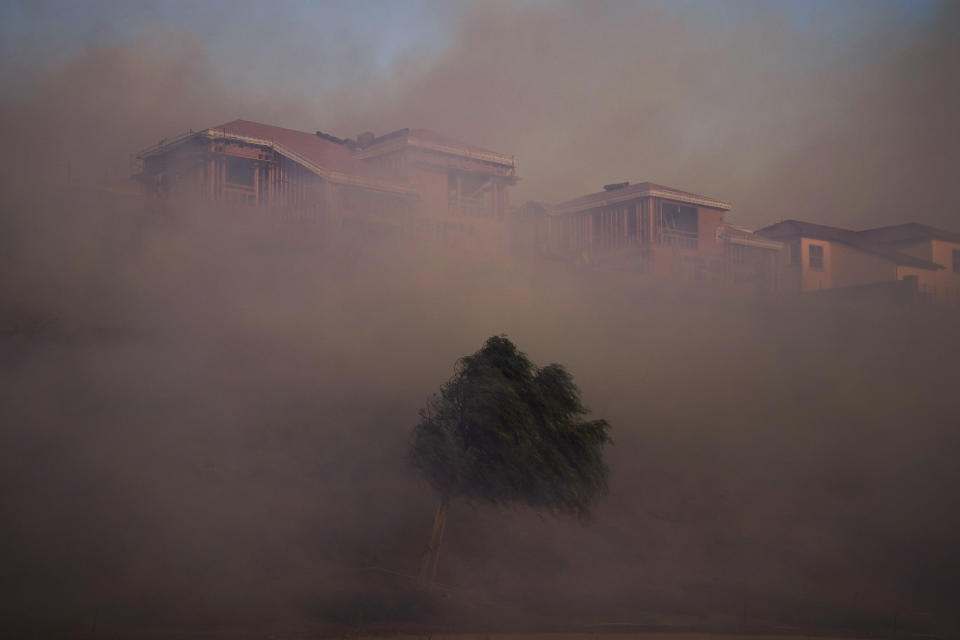 Gusting winds carry smoke from the Silverado Fire into residential areas Monday, Oct. 26, 2020, in Irvine, Calif. A fast-moving wildfire forced evacuation orders for 60,000 people in Southern California on Monday as powerful winds across the state prompted power to be cut to hundreds of thousands to prevent utility equipment from sparking new blazes. (AP Photo/Jae C. Hong)