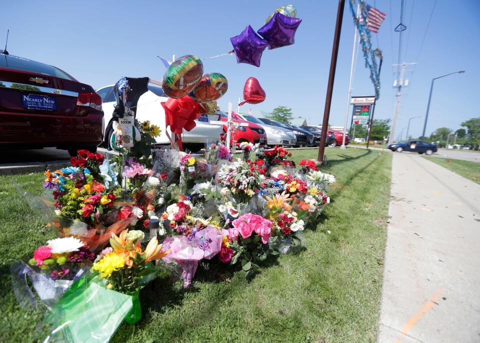 Dozens of flowers and other mementos are left at a memorial where three victims were killed in a two-vehicle crash on June 28, 2020, at Lombardi Avenue and Bart Starr Drive in Green Bay.