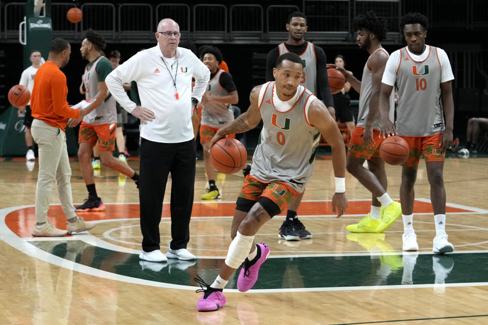 Miami's Matthew Cleveland (0) does drills as head coach Jim Larranaga, left, looks on during practice at media day for the Miami NCAA college basketball team, Monday, Oct. 23, 2023, in Coral Gables, Fla. (AP Photo/Lynne Sladky)