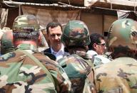 FILE - This Aug. 1, 2013 file photo posted on the official Facebook page of the Syrian Presidency, shows Syrian President Bashar Assad talking with soldiers with during Syrian Arab Army day in Darya, Syria. As the Syrian conflict entered its forth year this month and large parts of the country are either destroyed or under opposition control, Syrian officials say the presidential elections will be held on time later this year.The opposition rejects such a move saying after the death of more than 140,000 people and millions turned to refugees or displaced, Assad should step down rather than run again. (AP Photo/Syrian Presidency via Facebook, File)